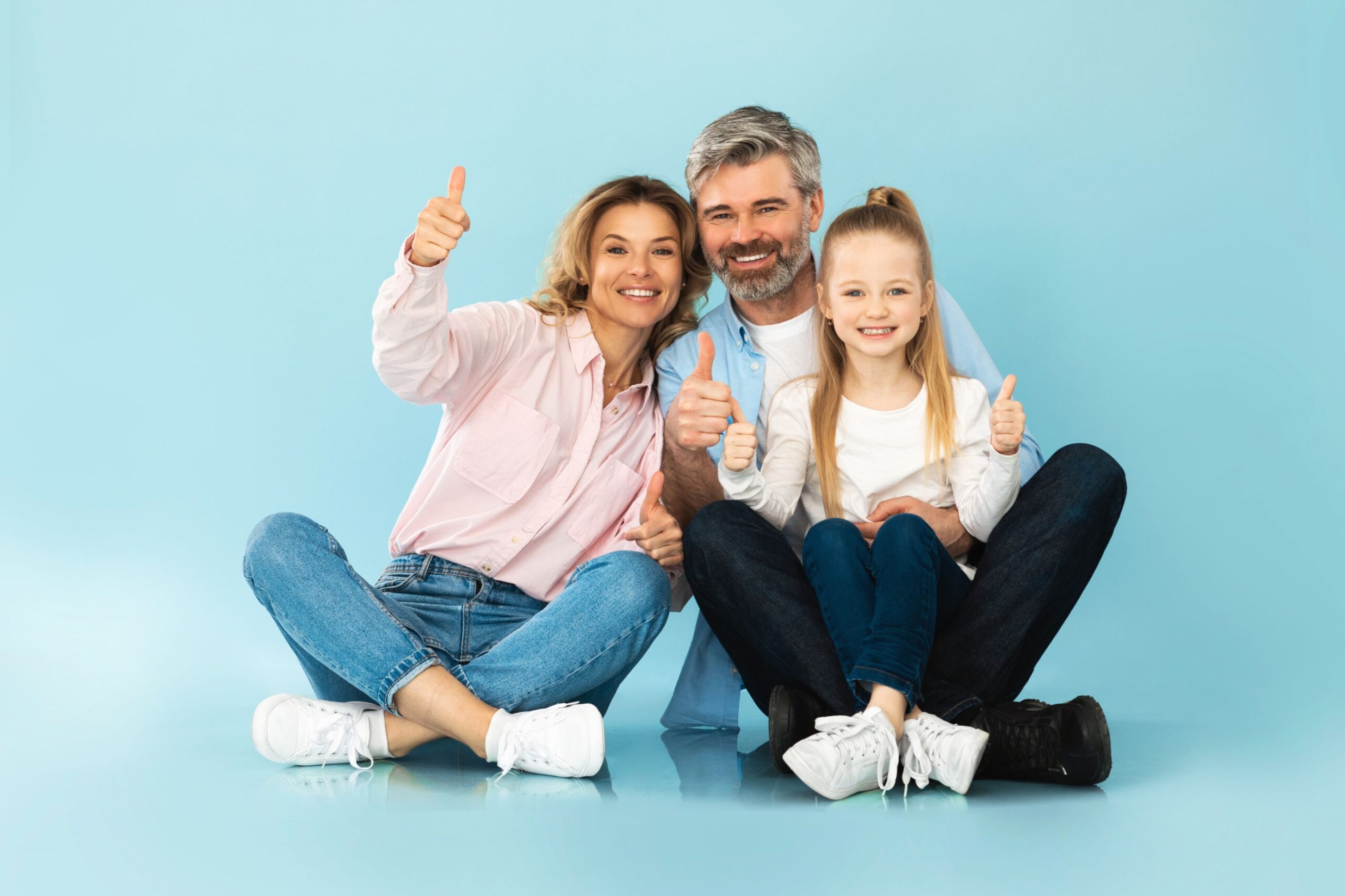 happy-family-gesturing-thumbs-up-smiling-sitting-blue-background